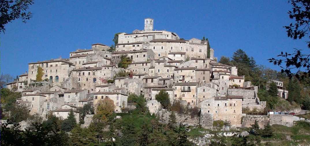 Hilltop town with dense stone buildings and a tower under a clear blue sky